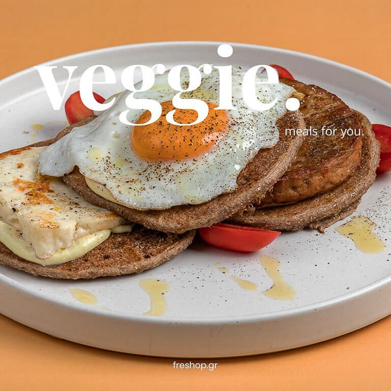 white plate with savory waffles with fried egg, tomatoes, and a design with the word ''veggie''