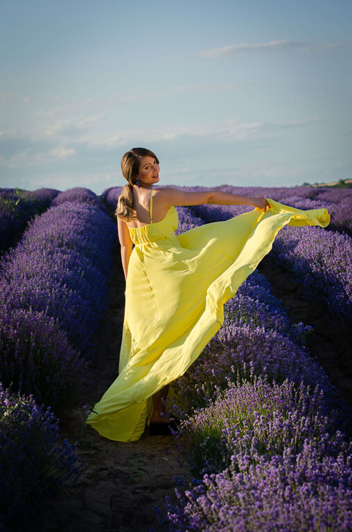 woman smiling in a yellow dress and a blue sky