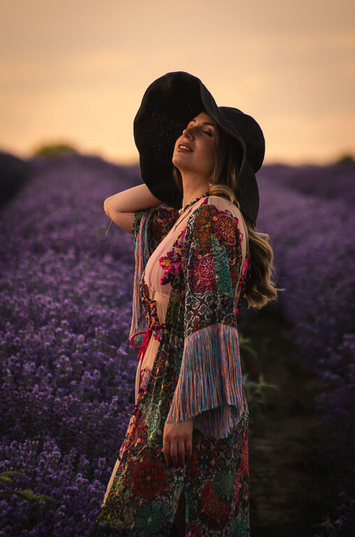 a woman is looking at the camera and smiling in a field of purple flowers