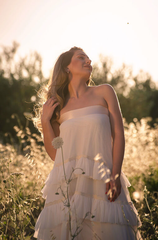 woman in a white dress stroking her hair in a field