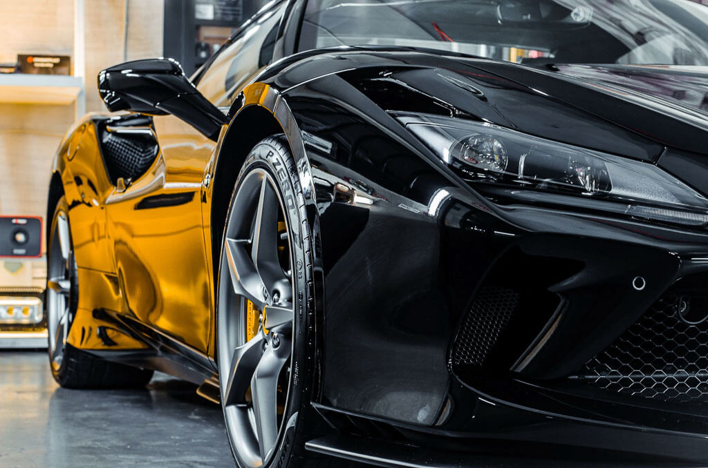 a black sports Ferrari in a garage diagonal half