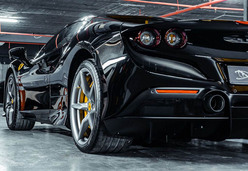 A black Lamborghini jeep in a garage with smoke and the lights on from a diagonal position