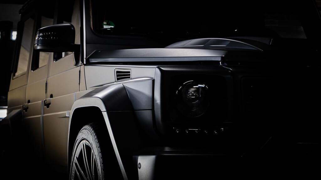 a black Mercedes jeep in a diagonal front position with the light touching the side