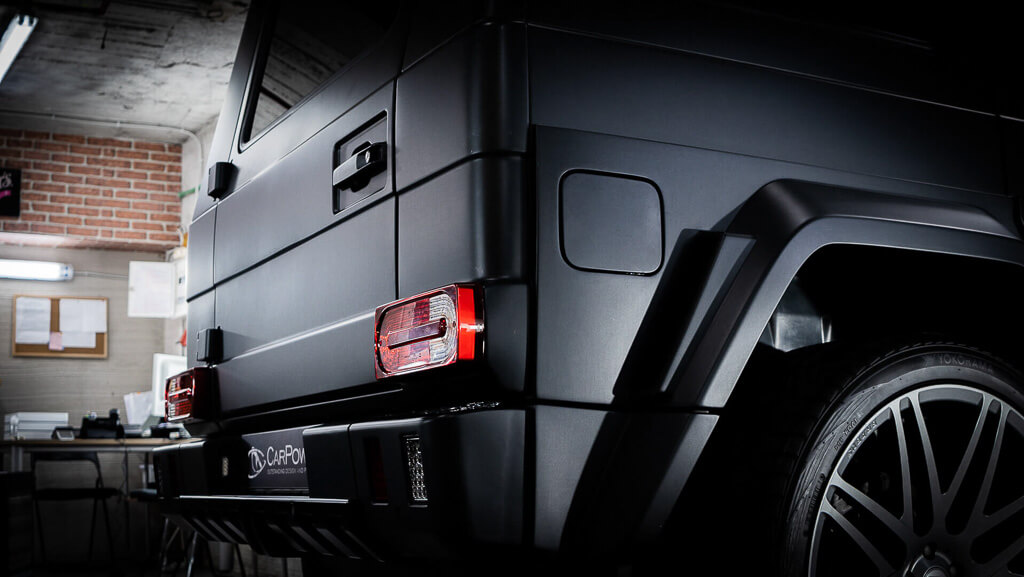 a black Mercedes jeep in a diagonal rear position with the light on the side in a garage