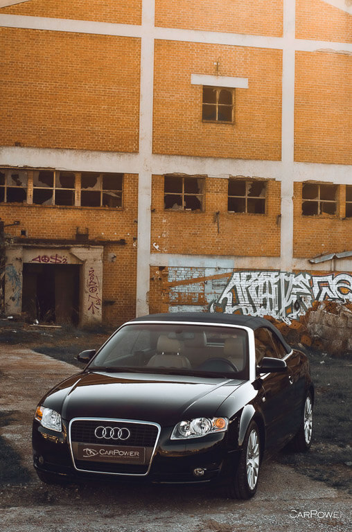 an Audi black car was photographed from above in front of an old building with graffiti