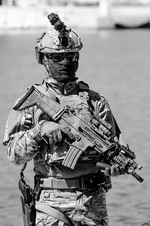 white and black photograph of a soldier in uniform and mask holding an automatic weapon.