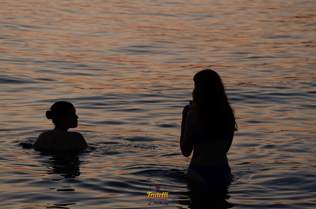 dark photo of two women standing in their swimsuits in the sea