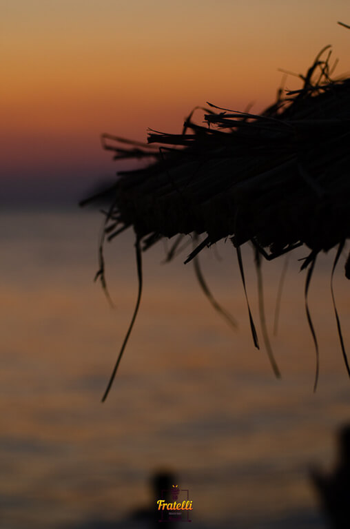 dark photo with the sunset light and a beach umbrella in front of it