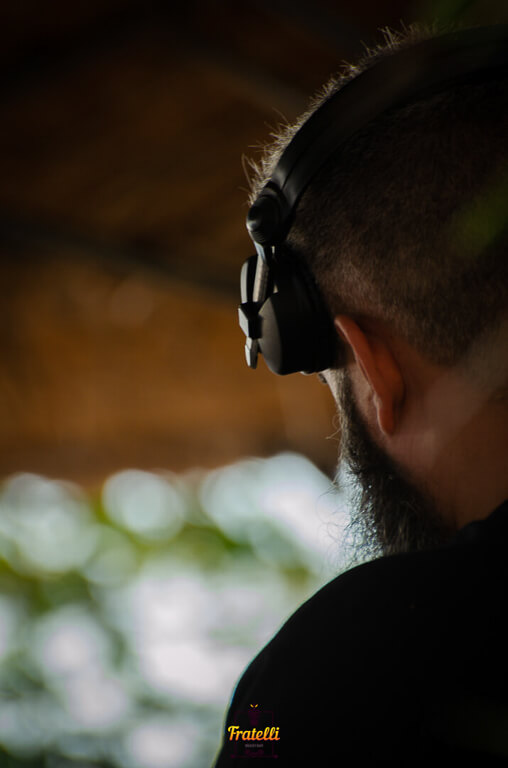 A man with DJ headphones on his head is back, wearing a black shirt