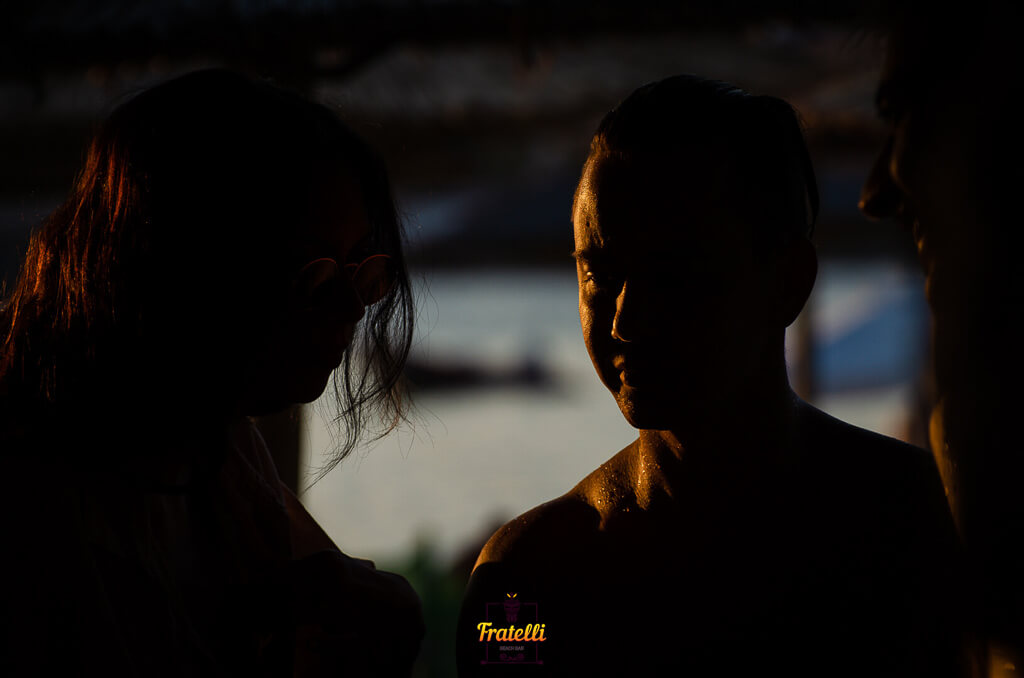 dark photo of a girl and two boys on the beach talking