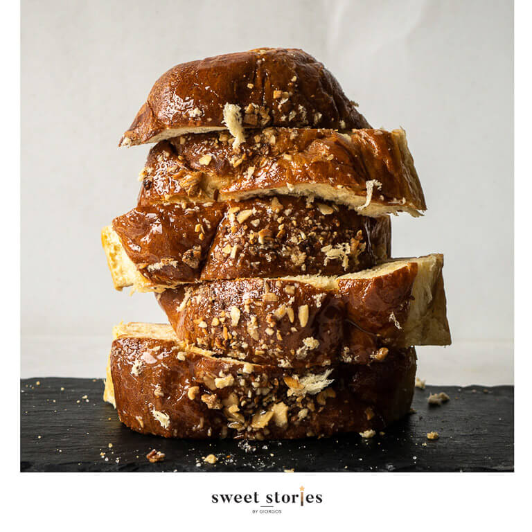 sliced brioche slices one on top of the other on a black plate on a white background.