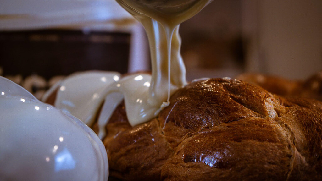 the pastry chef pours white chocolate on a bun