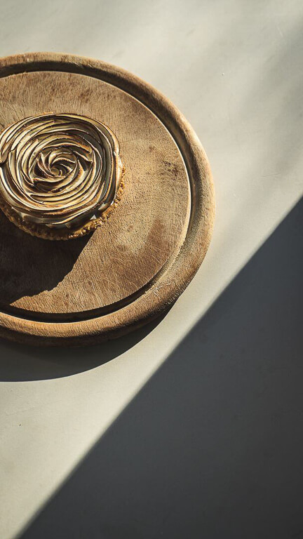 wooden base with sweet-tart in the middle in the shape of a rose on a bench and next to it is a shadow