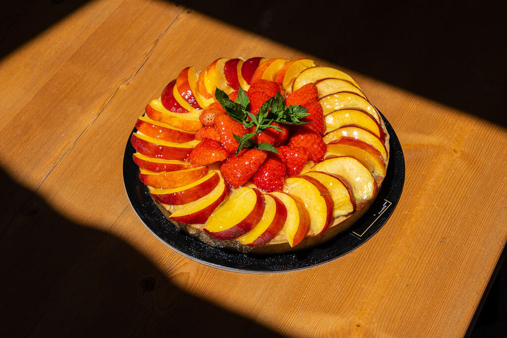 peach pie with strawberries on a base with the sunlight falling on the wooden table