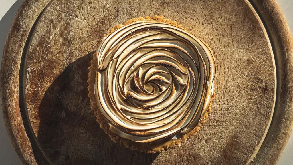 wooden base above a white table with a rose-shaped sweet tart in the middle