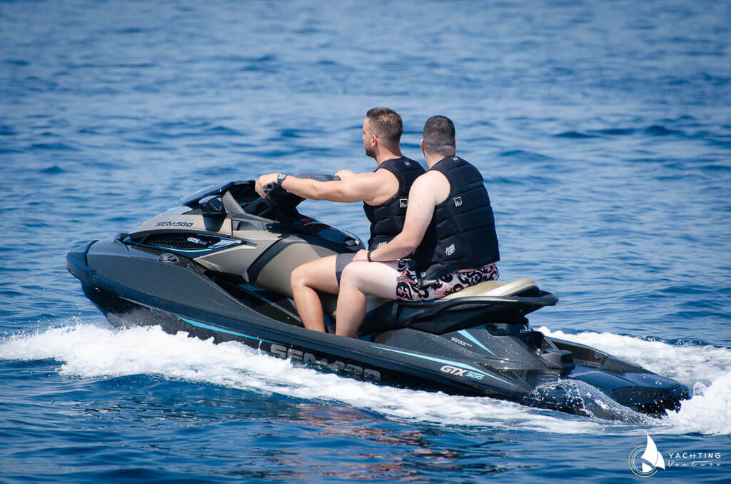 two men on a jet ski in the sea with their swimsuits.