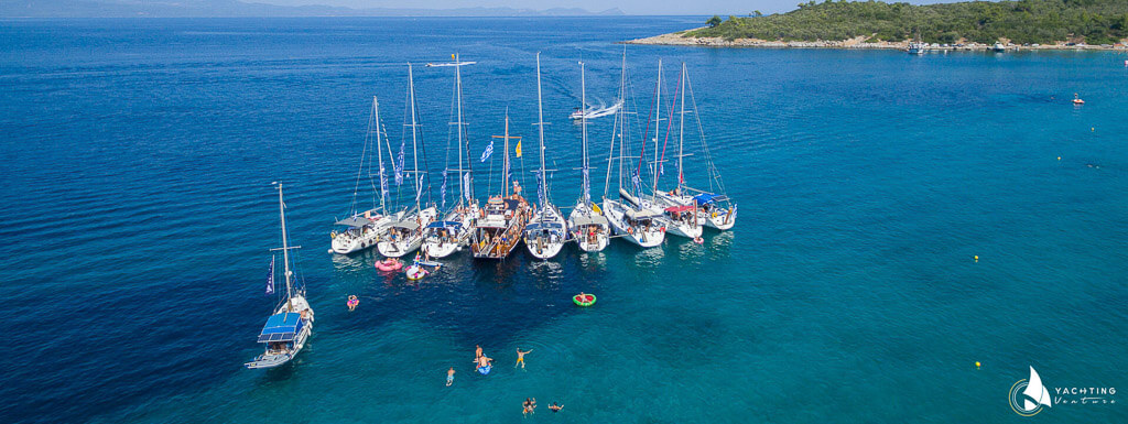 panoramic drone photo showing ten boats in the blue sea and two more in motion