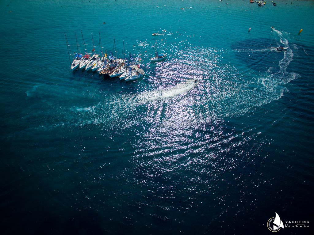 panoramic drone photo showing ten boats in the blue sea and two more in motion