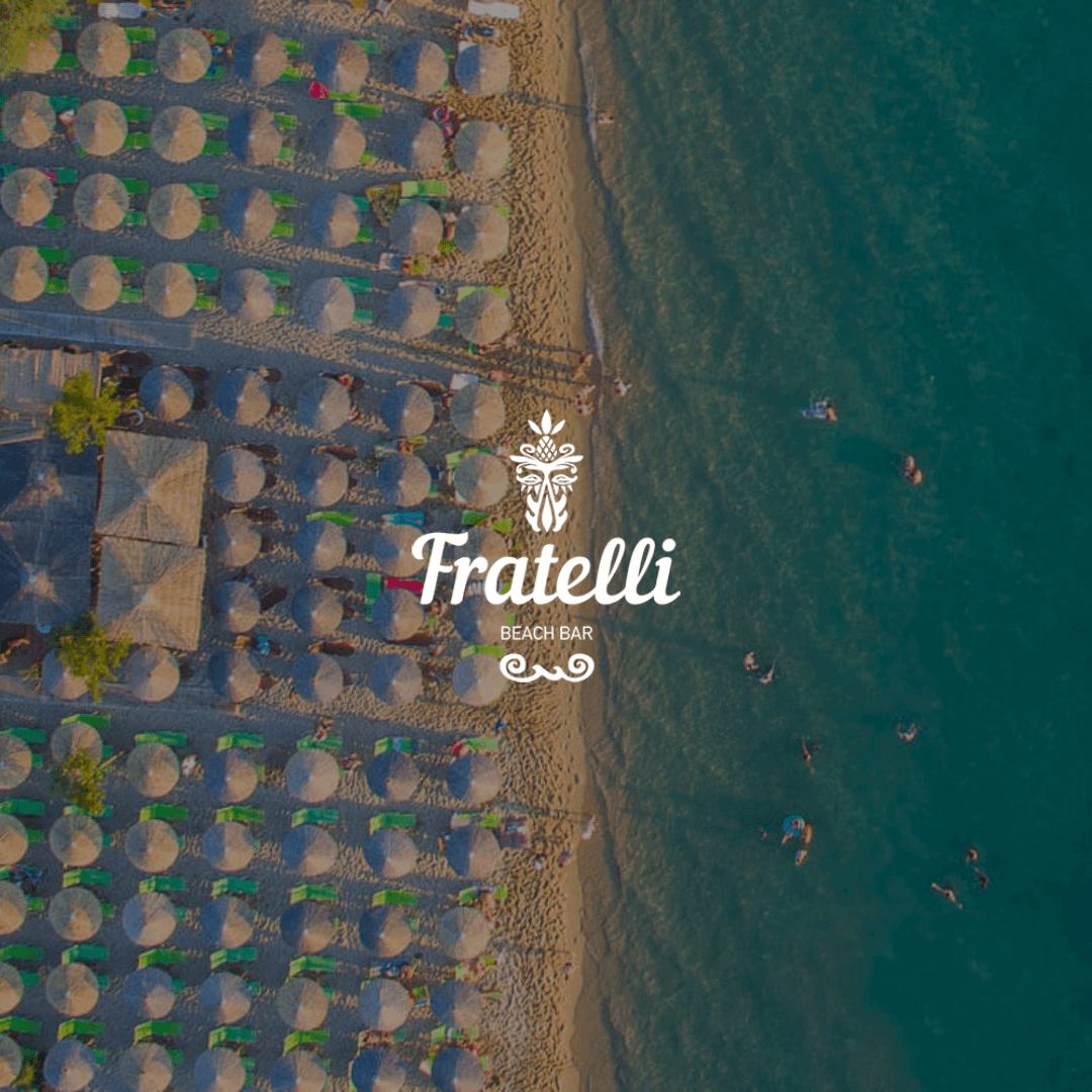 drone photo showing a beach bar with wooden umbrellas, the beach, and the sea